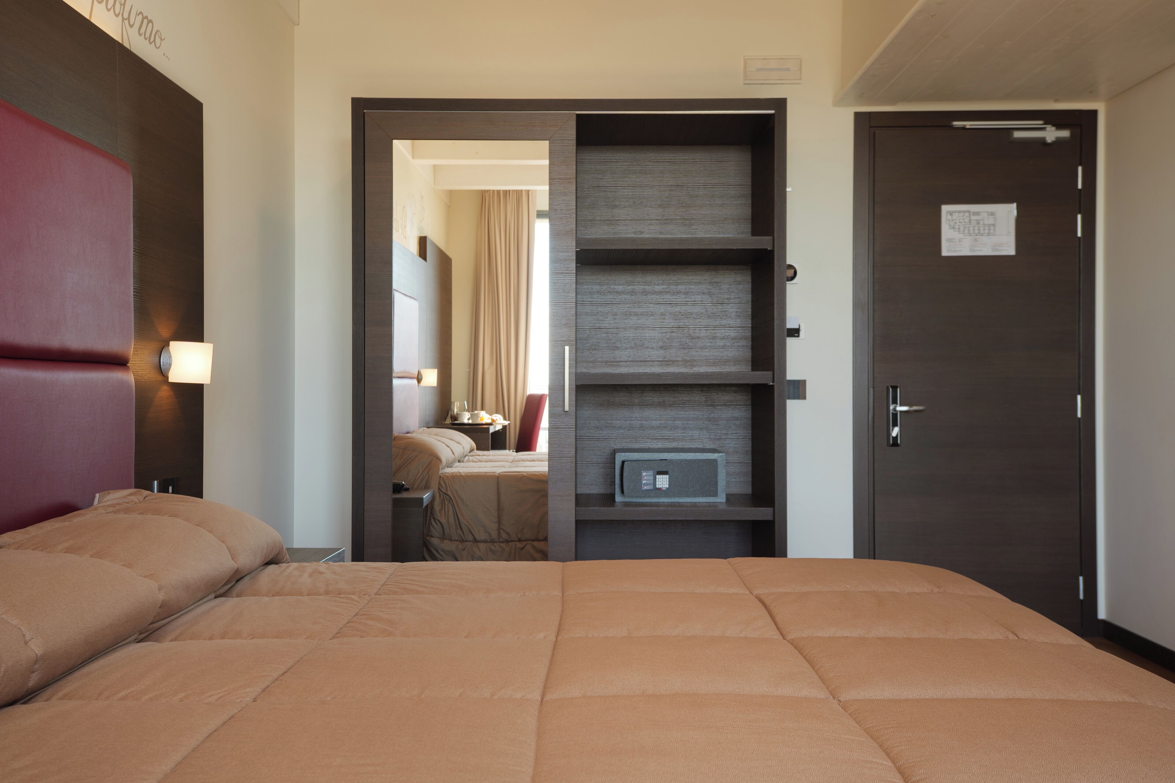 Une chambre d’hôtel avec un grand lit, une armoire et un bureau avec une lampe.