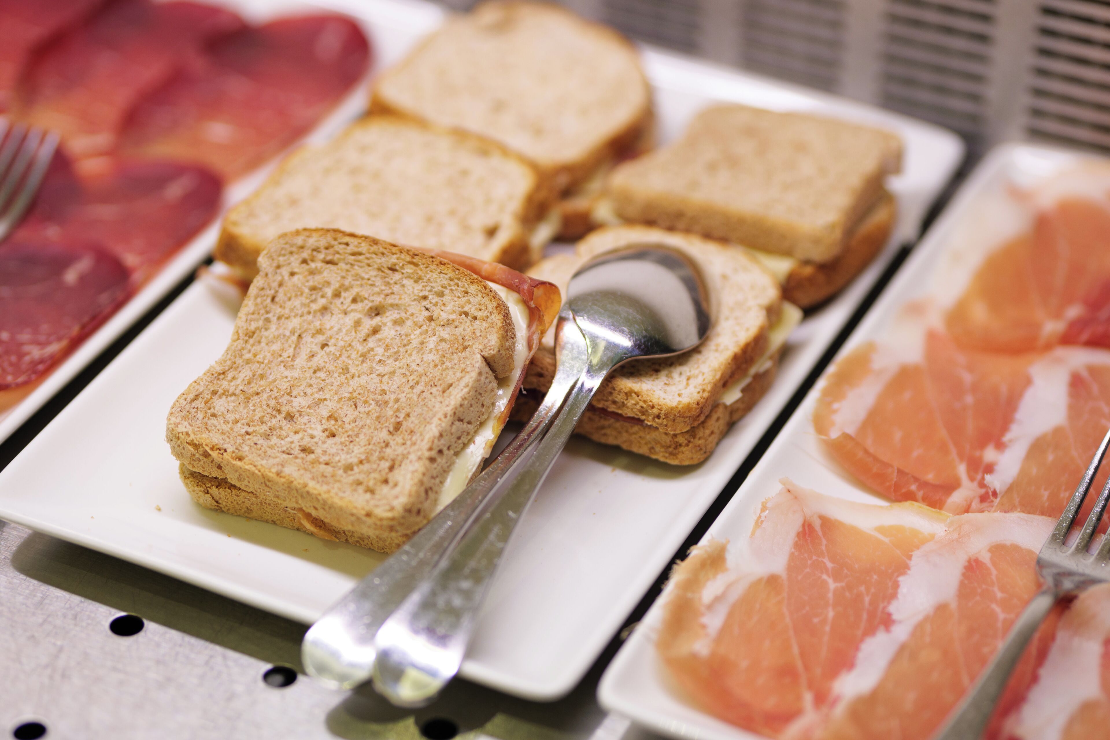 Un bufé de desayuno con diferentes opciones de comida, incluyendo tostadas, jamón y gajos de pomelo.