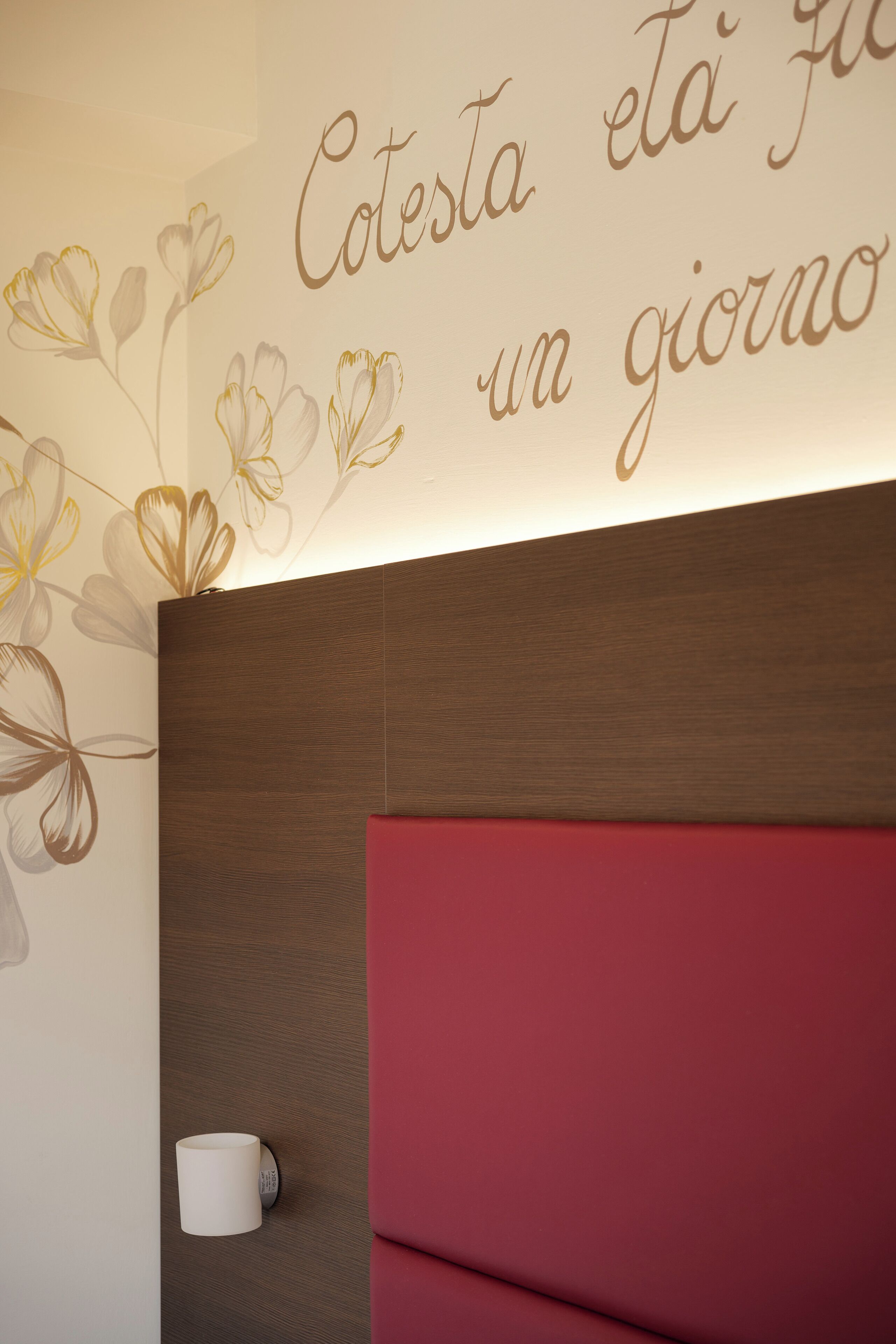 A wall with a floral design and a wall-mounted cup holder.