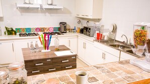 Una cocina con armarios blancos, una encimera con cafetera, tostadora y frutero.