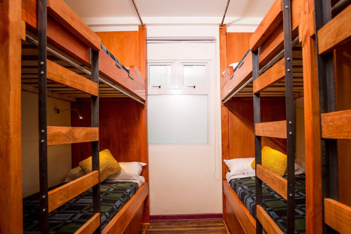 A narrow corridor with bunk beds on either side, leading to a door with frosted glass panels.