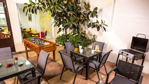 Un comedor con mesa de fútbol de mesa, una parrilla y una planta grande en maceta.
