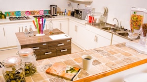 Una cocina moderna con armarios blancos, una isla central con taburetes y diversos electrodomésticos.