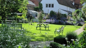 A white house with a pitched roof, surrounded by a well-maintained garden with flowers and shrubs. - St Ethelwolds House (Abingdon)