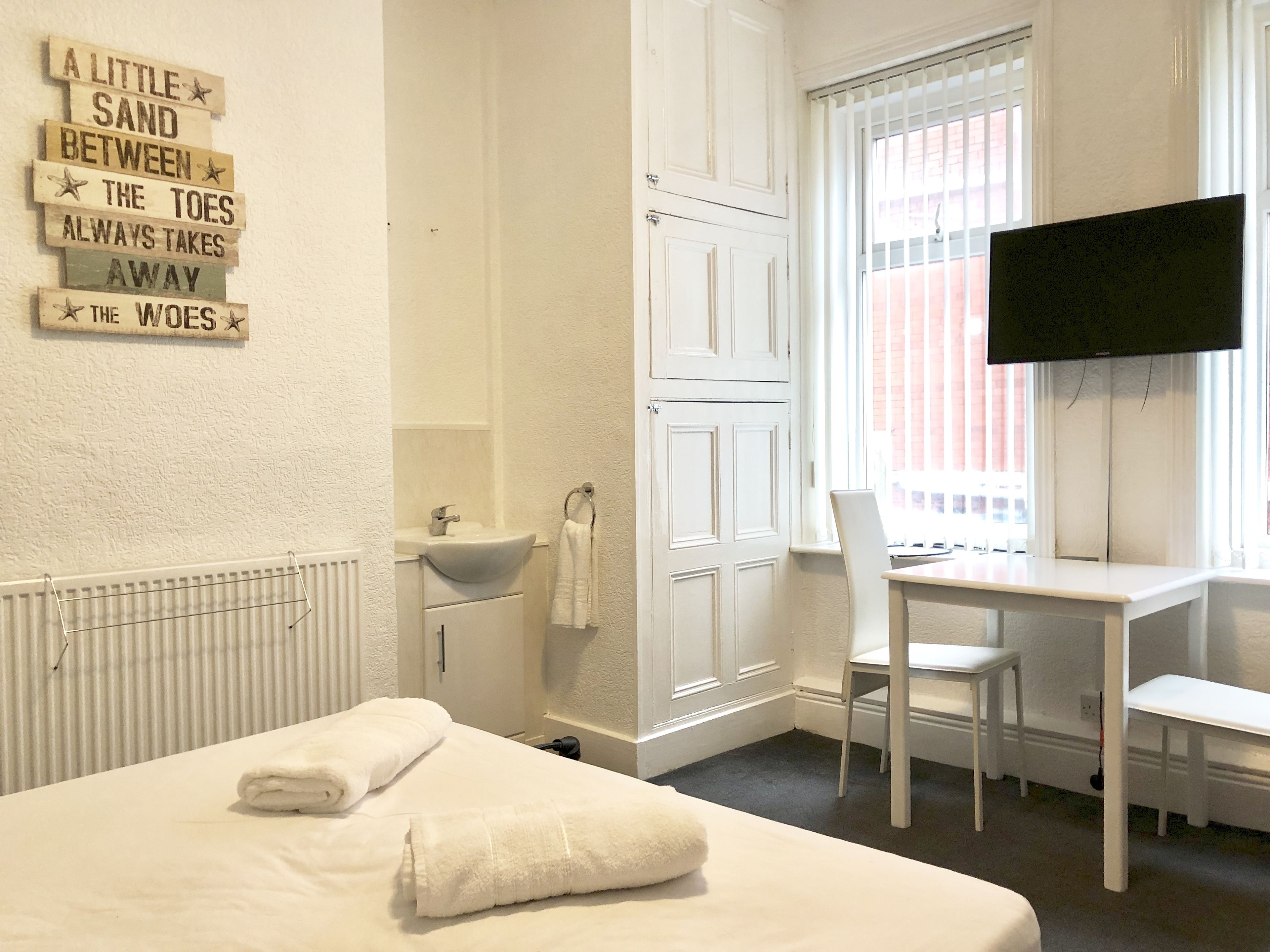 Une chambre d’hôtel équipée d’un lit, d’un bureau, d’une chaise, d’une télévision, d ’une fenêtre et d’un panneau fixé au mur.