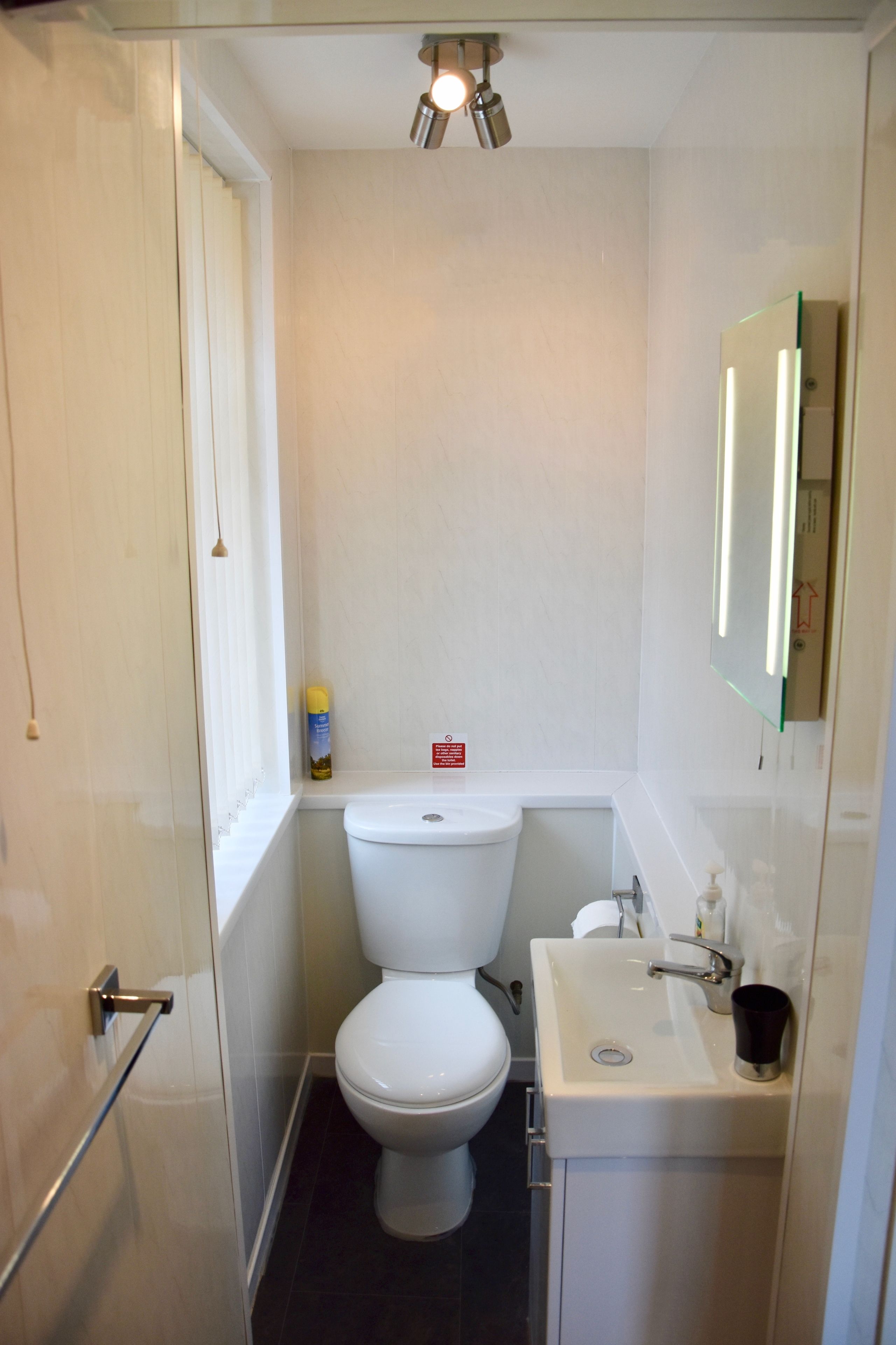 A compact bathroom with a toilet, sink, and mirror.