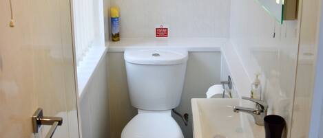 A compact bathroom with a toilet, sink, and mirror.