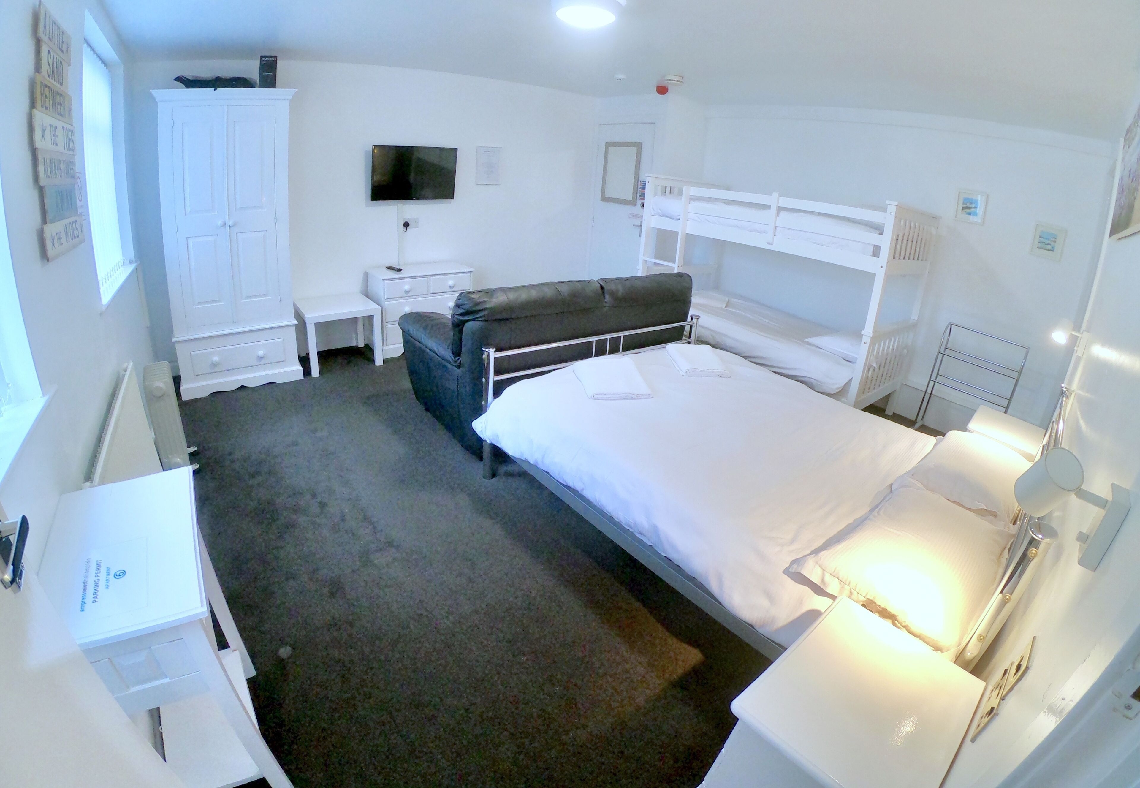 Ein Hotelzimmer mit Etagenbett, Schreibtisch, Kleiderschrank und Fernseher.