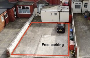 Een dakterrasparkeerplaats met een witte auto geparkeerd in een aangeduid vak.