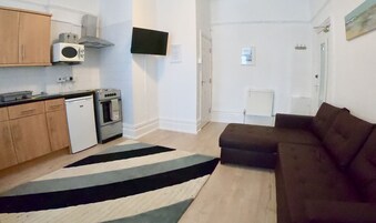 Un espacio habitable pequeño con kitchenette, un sofá y un tapete a rayas.