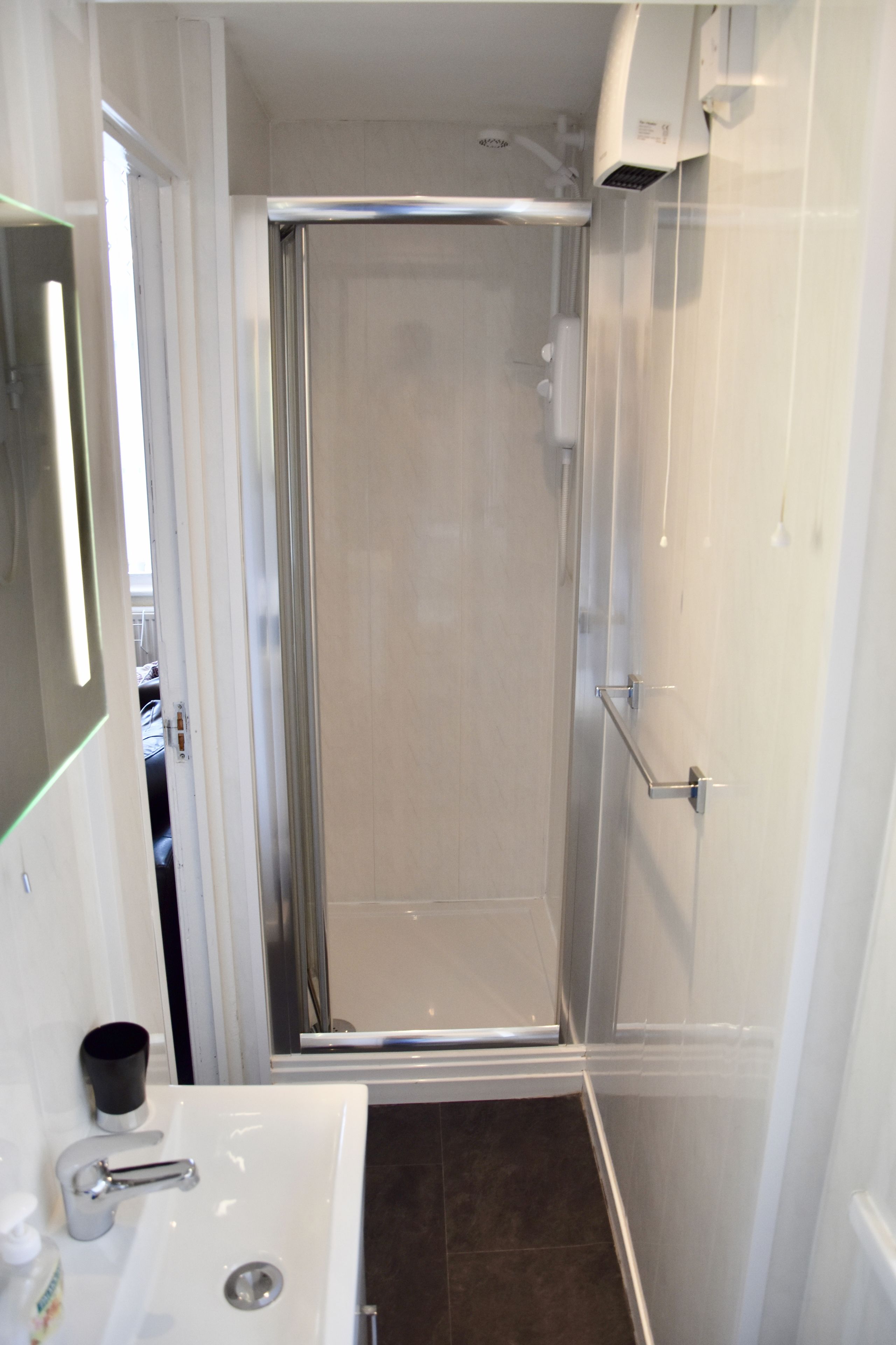 Une salle de bain avec une douche, un lavabo et un miroir.