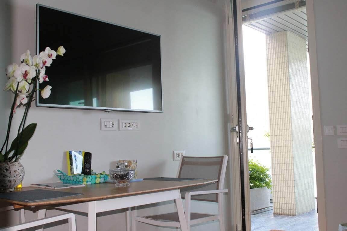 Un coin repas avec une table et des chaises, un téléviseur fixé au mur et une plante en pot.