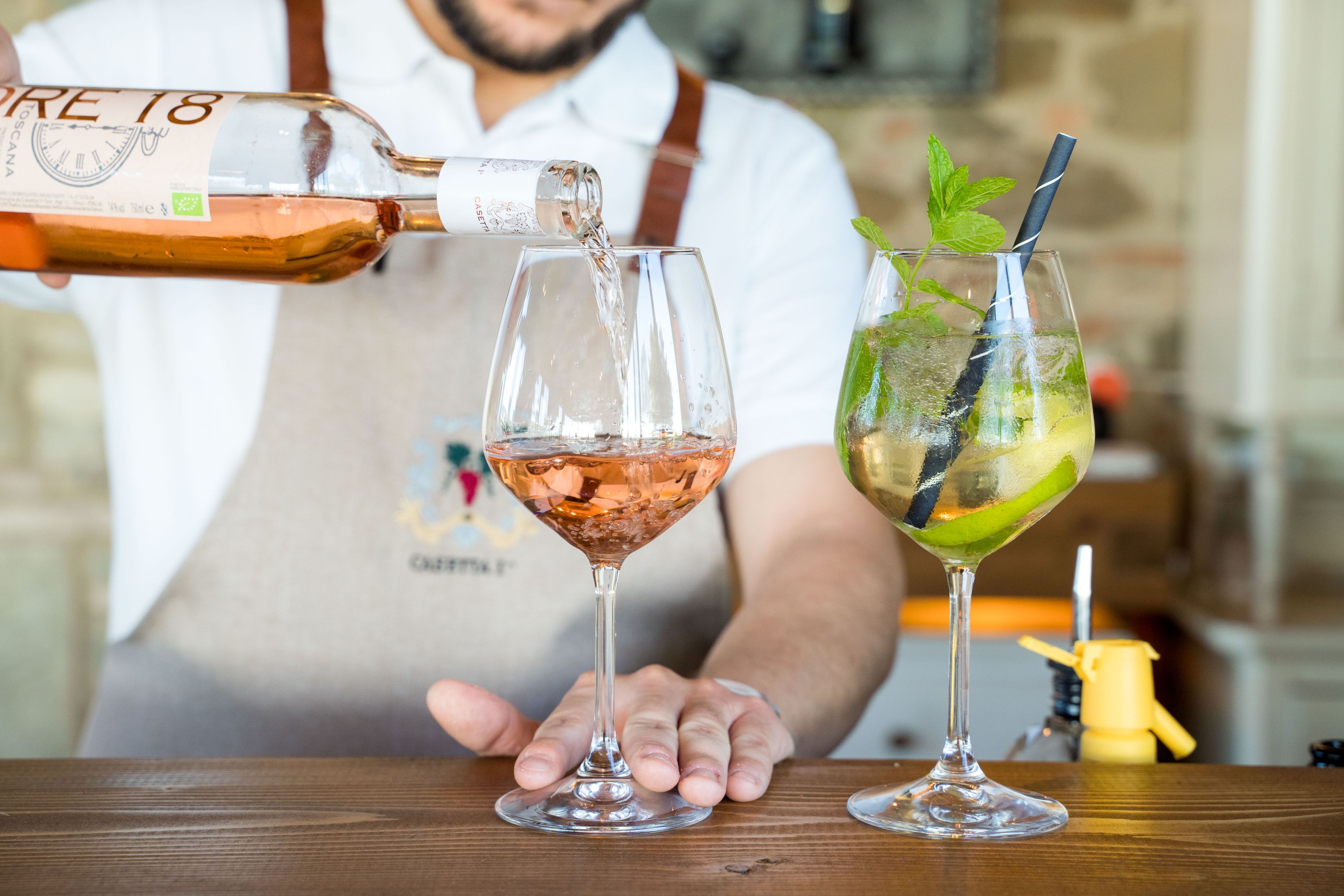 A bartender pouring a drink into a martini glass.