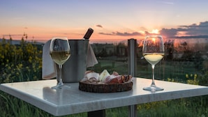 Una mesa con dos copas de vino blanco, un recipiente metálico y una tabla de madera con alimentos.