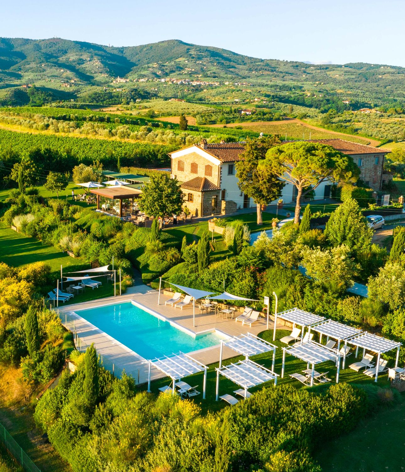 Une villa avec piscine, entourée d’une végétation luxuriante et de collines.