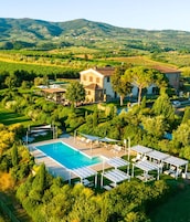 Una villa con piscina, rodeada de exuberante vegetación y colinas.
