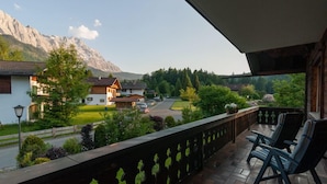 Un balcón con dos sillas, con vistas a una zona residencial con casas y montañas al fondo.