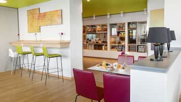 A modern dining area with a counter, bar stools, and a table set for breakfast.