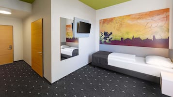 A hotel room with a bed, a desk, a TV, and a large wall mural.