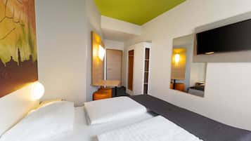 Een hotelkamer met een bed, een televisie, een schilderij en een groen plafond.