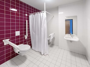 Une salle de bain moderne avec des toilettes blanches, un rideau de douche et un lavabo avec un miroir.