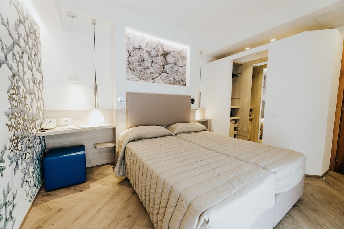 A modern bedroom with a bed, bedside table, and a wall-mounted artwork.