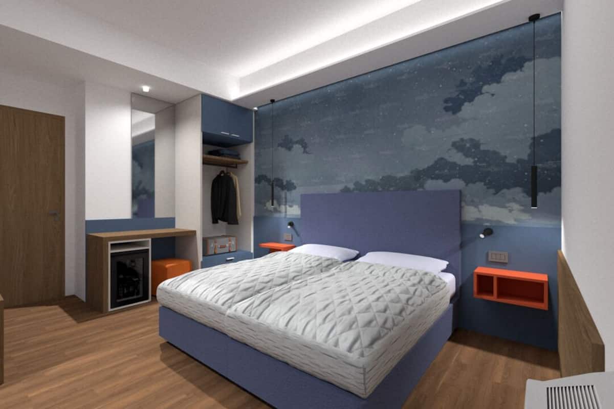 A modern bedroom with a large bed, a wardrobe, a desk, and a nightstand.