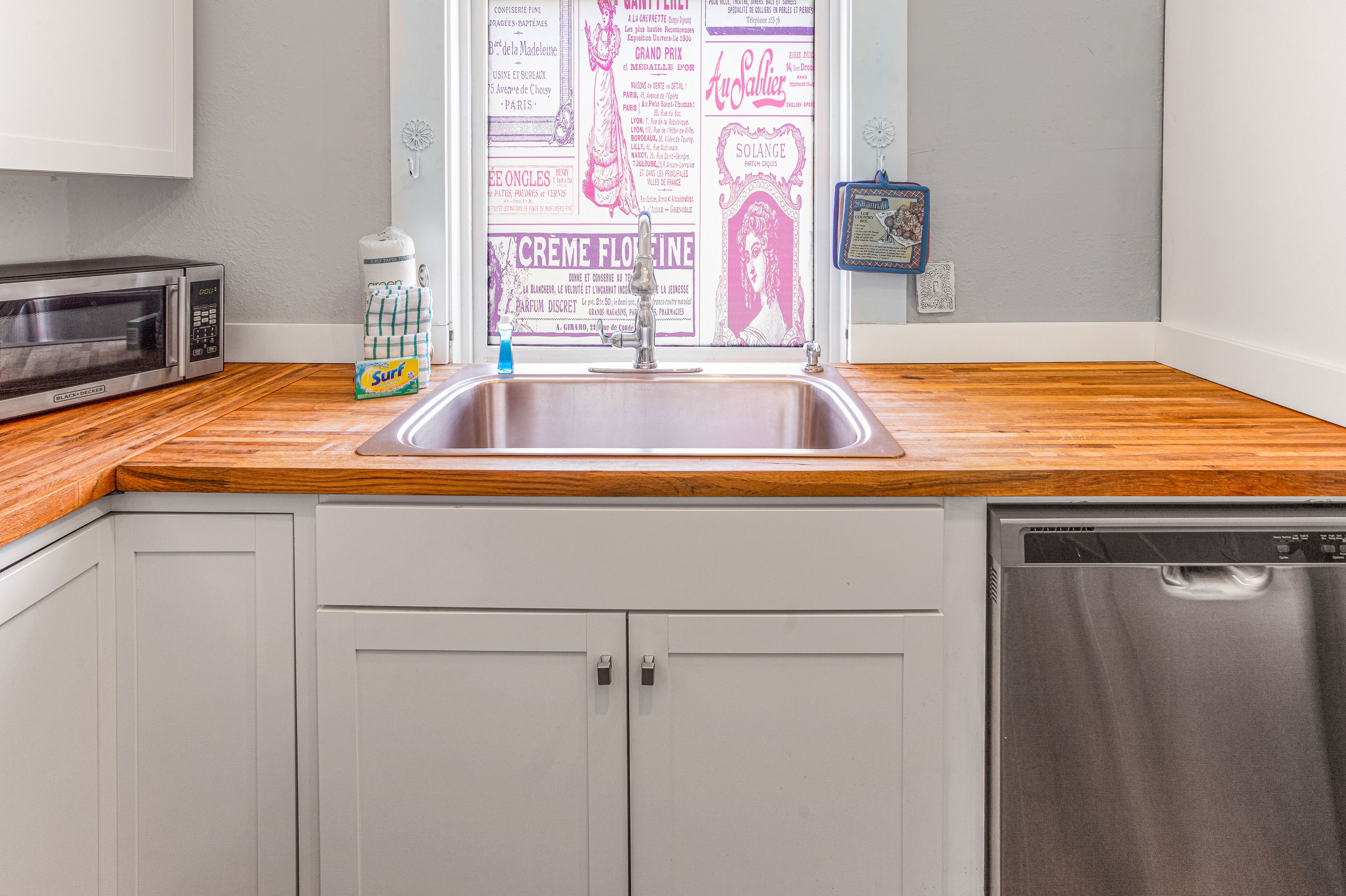 A kitchen with a stainless steel microwave, a sink, and a dishwasher.