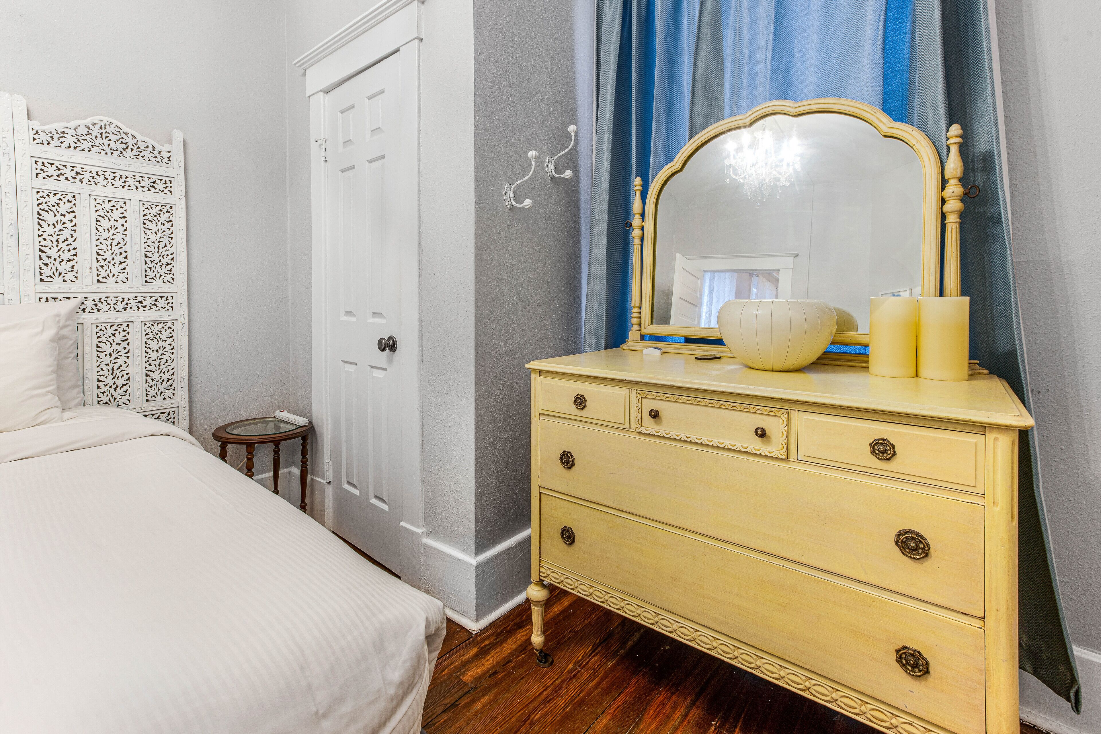 A bedroom with a bed, a dresser with a mirror, and a small round table.