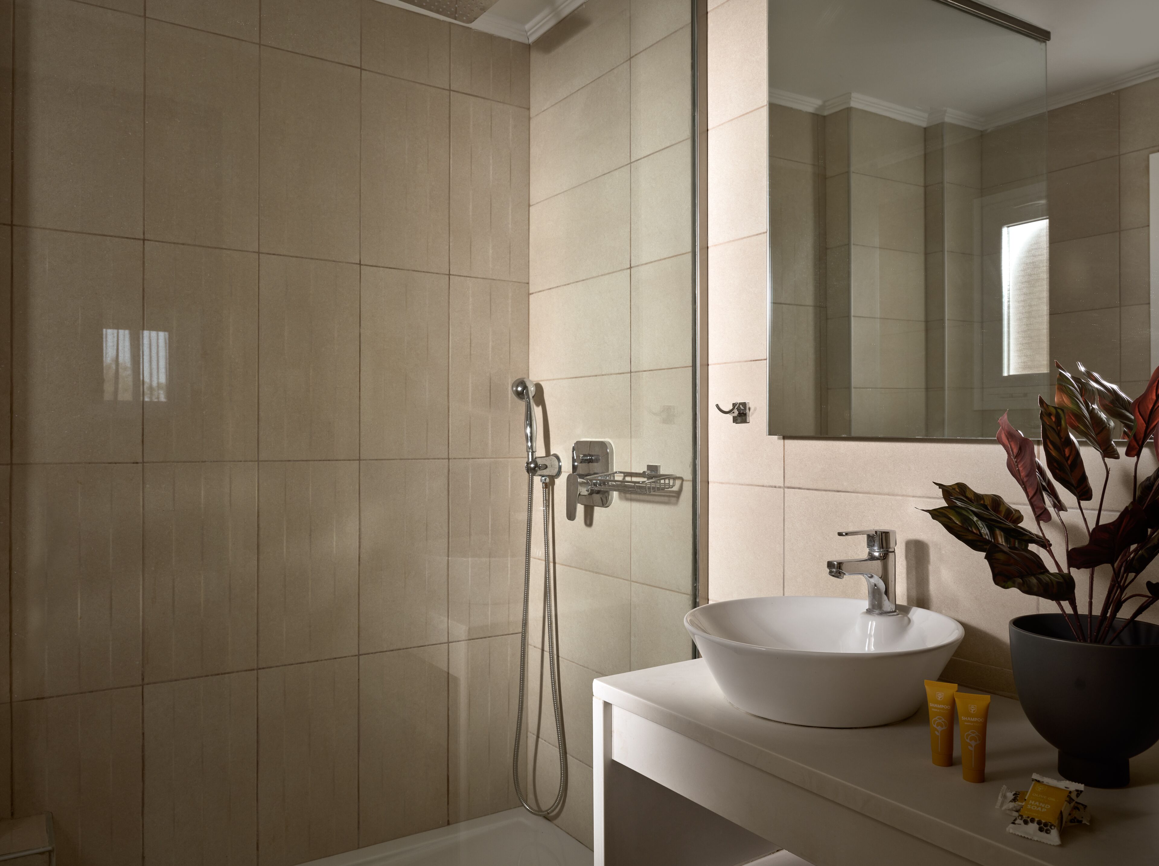 A modern bathroom with a large mirror, a white sink, and a shower area.