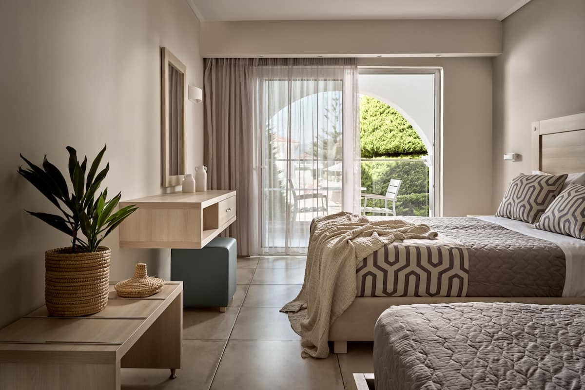 A modern bedroom with a bed, bedside table, and a large window with a view of greenery.