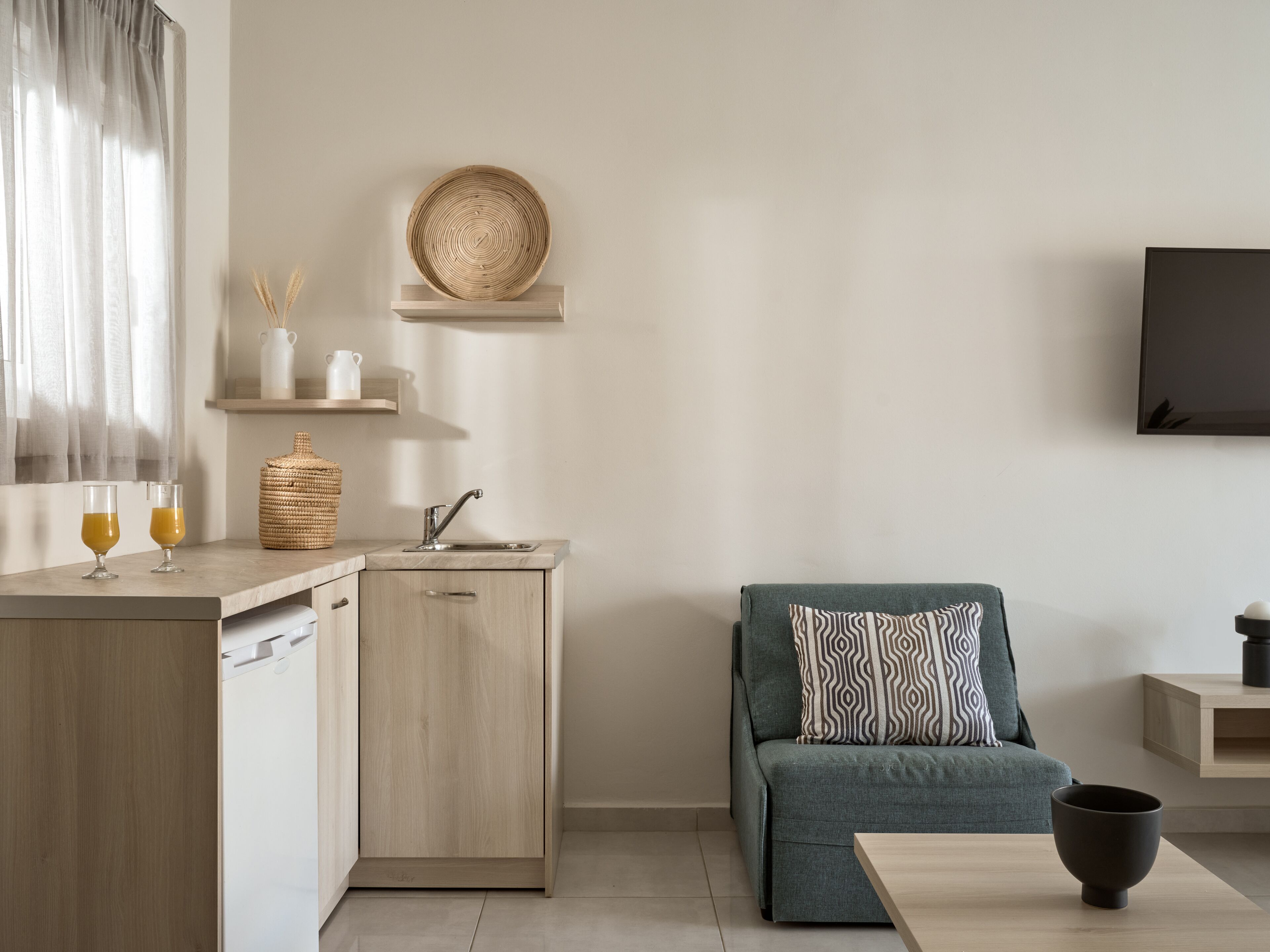 A modern kitchen with a built-in sink, a wooden cabinet, and a countertop with two glasses of orange juice.