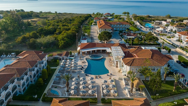 Vista aérea de un resort con piscina, varias construcciones y vista al mar.