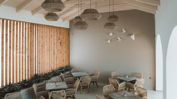 A restaurant with wicker furniture, hanging lamps, and a wooden slat wall.