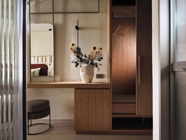 Un baño moderno con un tocador de madera, un espejo y un jarrón con flores secas.