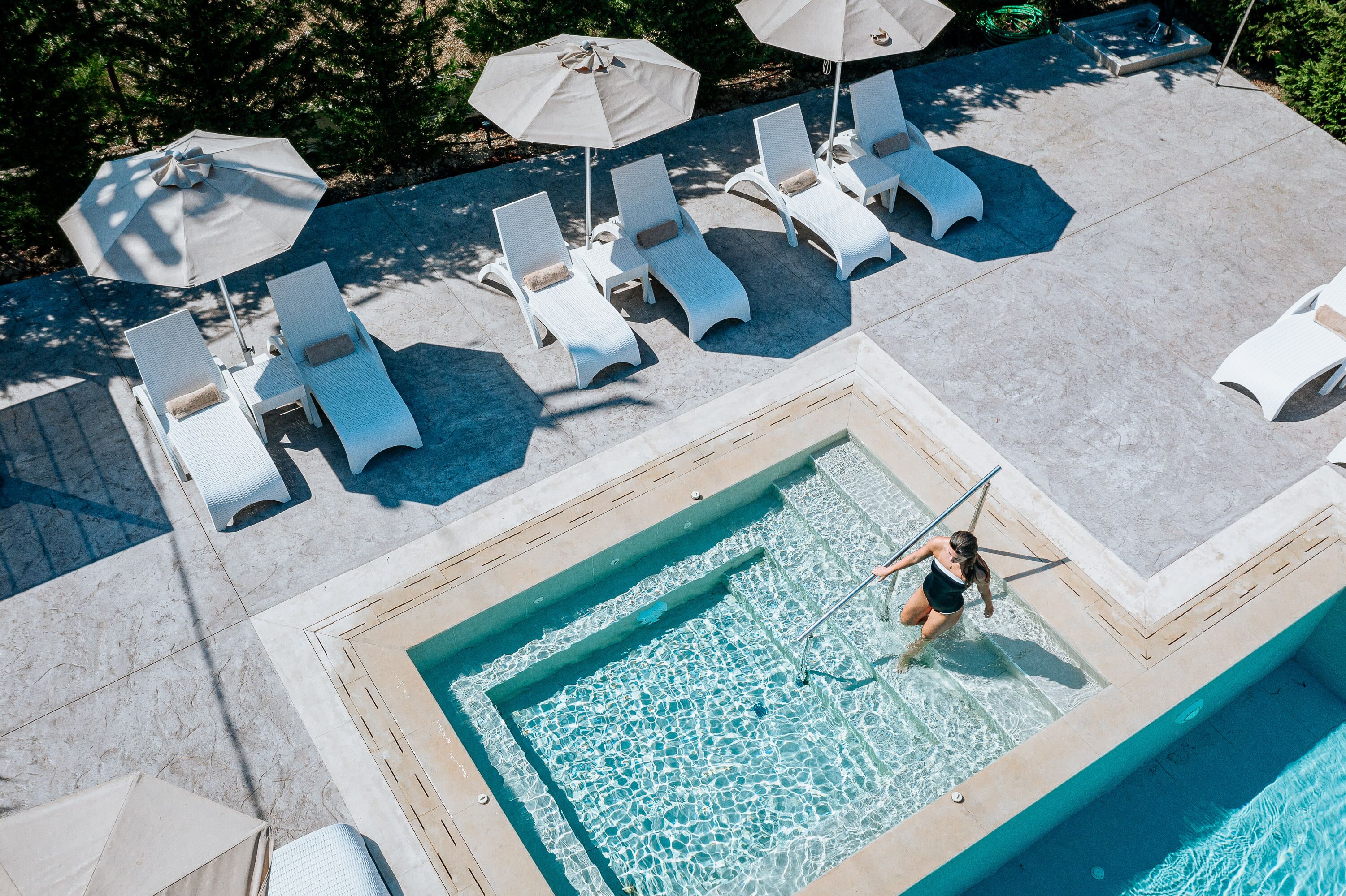 A rooftop pool area with lounge chairs and umbrellas.