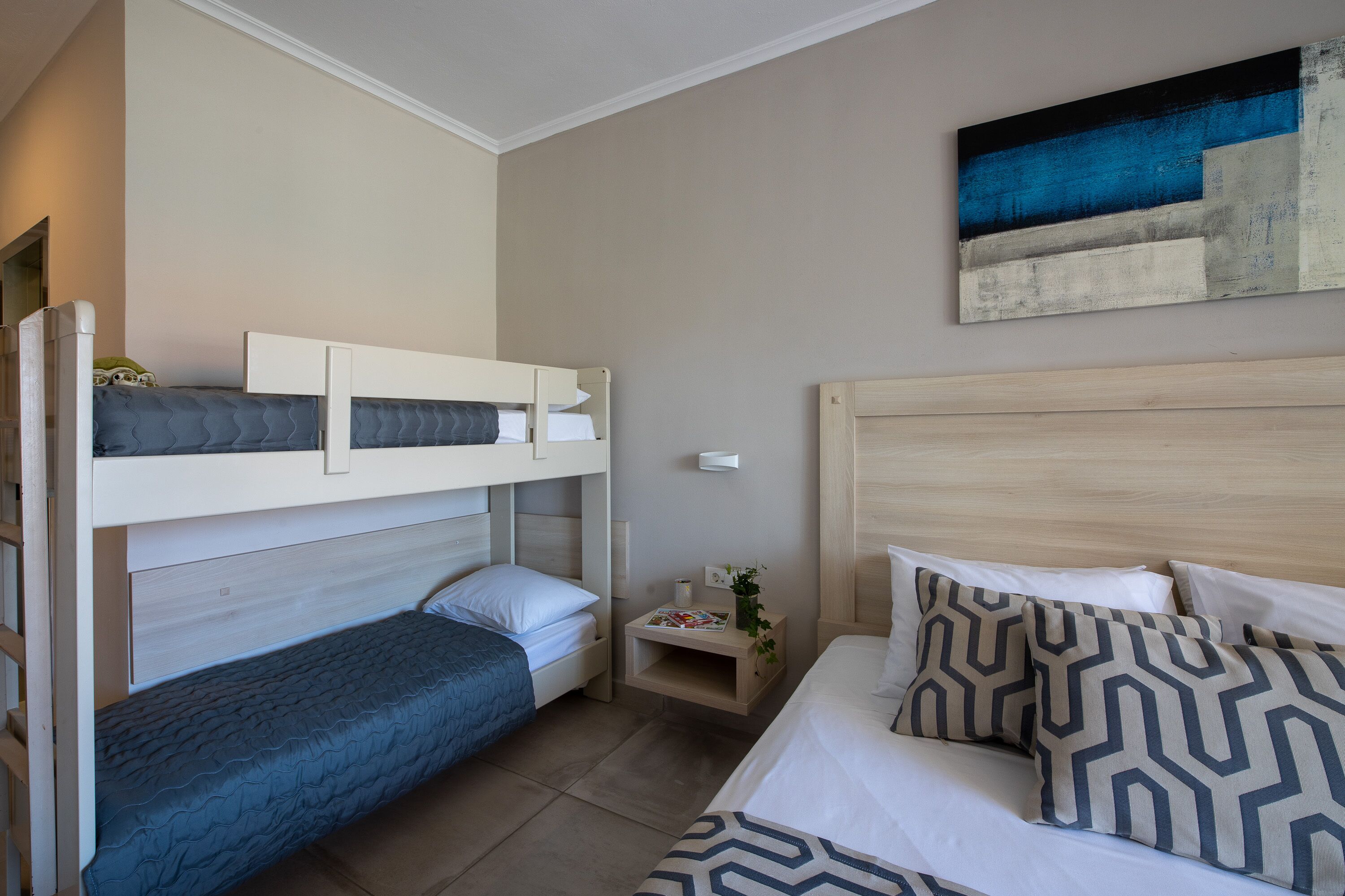 A bedroom with a bunk bed, a single bed, and a nightstand with a lamp.