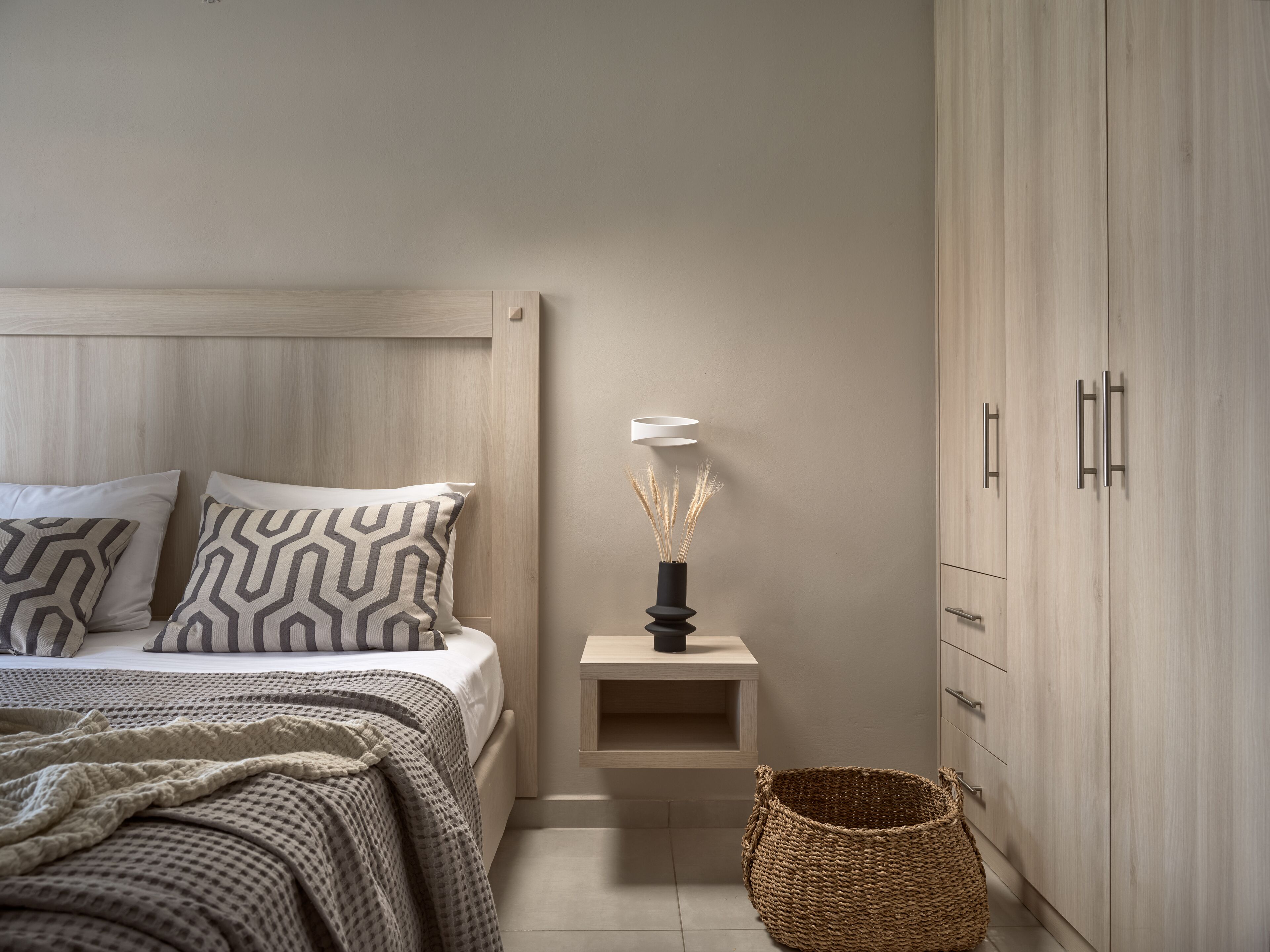 Une chambre à coucher avec un lit, une table de chevet, une lampe et une armoire.