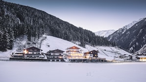 A multi-story hotel with a snow-covered landscape and mountains in the background.