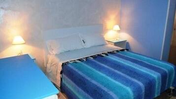 Una cama individual con un edredón a rayas, dos lámparas de noche y una mesita de noche.