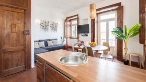 Una cucina moderna con piano di lavoro in legno, lavello in acciaio inossidabile e zona pranzo con tavolo e sedie.