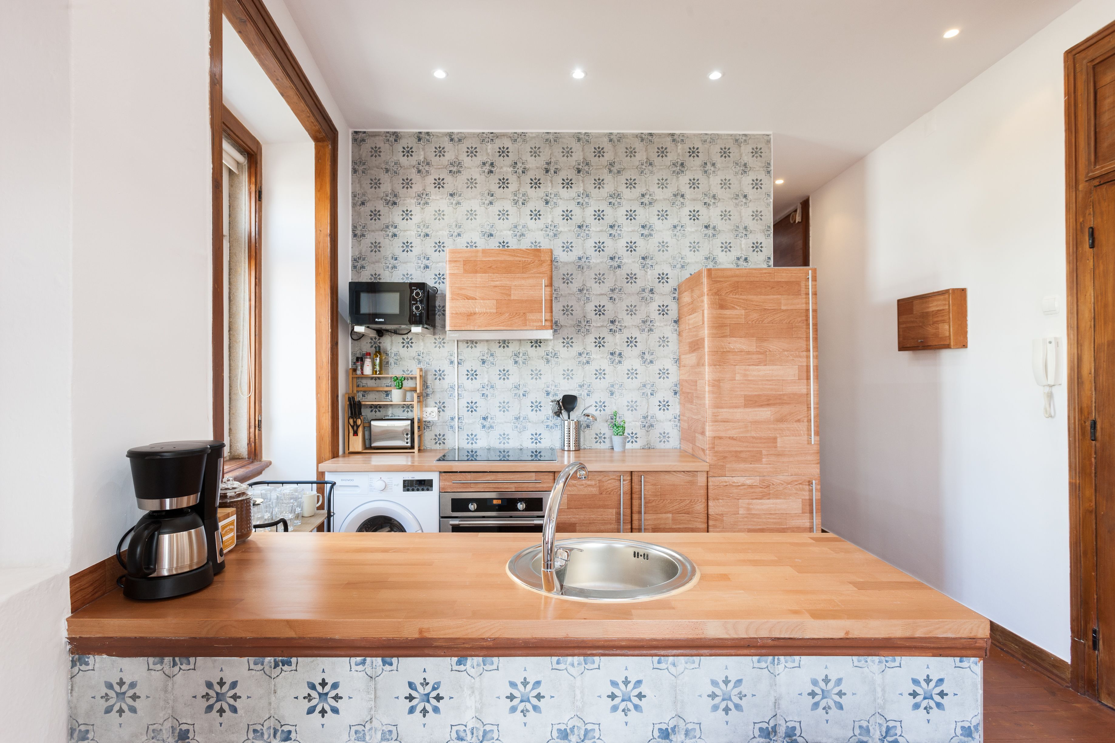 Una cocina con encimera de madera, pileta de acero inoxidable y un microondas.
