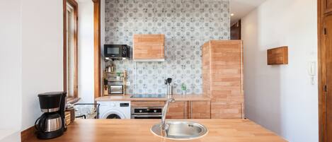 Una cocina con encimera de madera, pileta de acero inoxidable y un microondas.