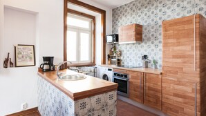 Una cucina compatta con mobili in legno, forno ventilato, microonde e macchina per il caffè.