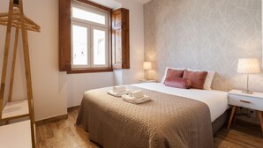 Una camera da letto ordinata con un letto grande, una scala di legno, una finestra con tende e un muro decorato.