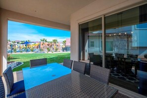Un patio con mesa y sillas, un ventanal de vidrio y vistas a un parque acuático.