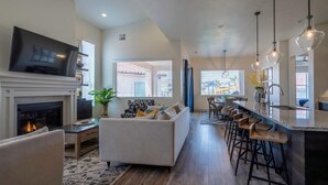 Una cucina moderna con isola centrale, sgabelli da bar e zona pranzo con un'ampia finestra.