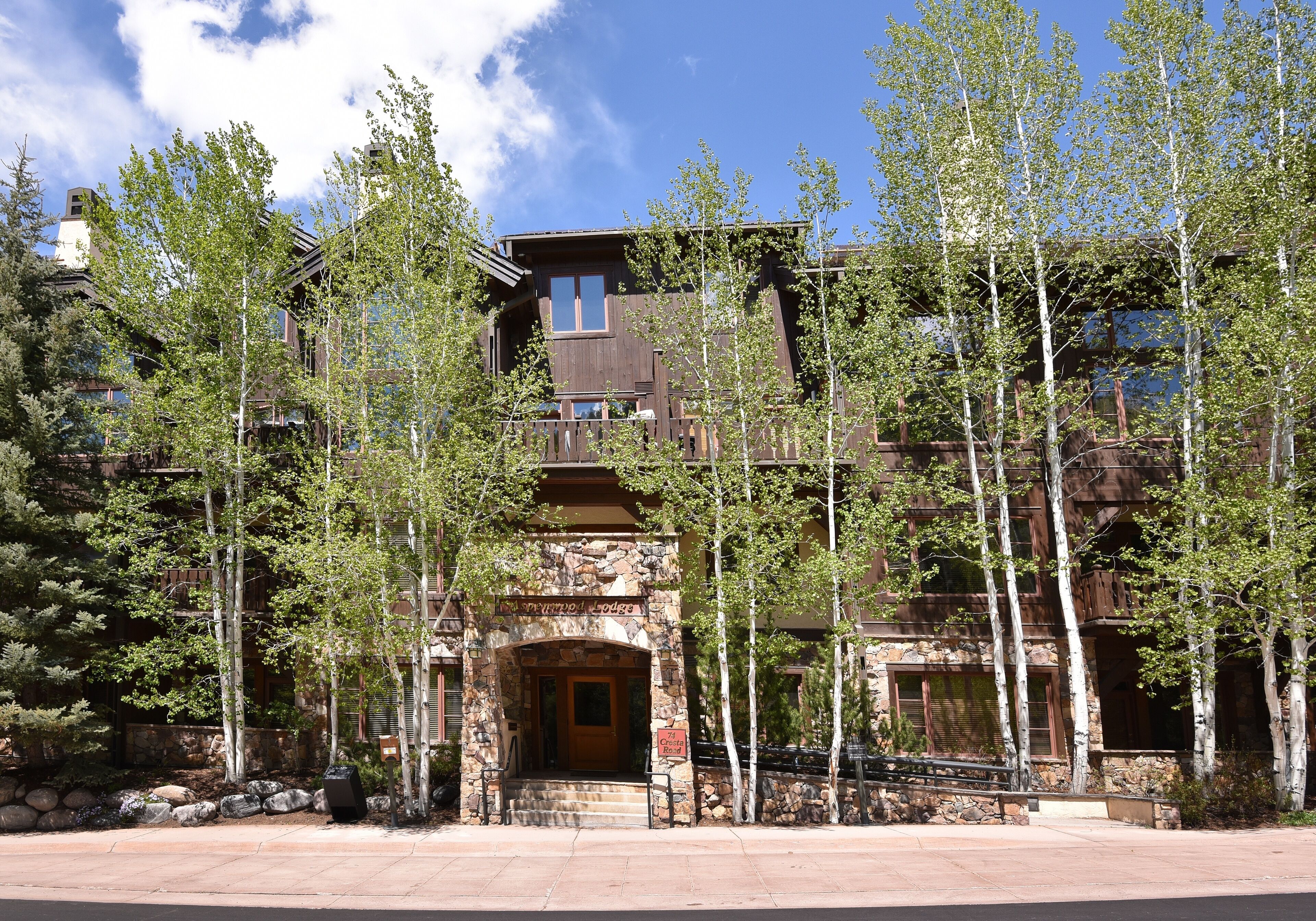 A multi-story lodge with a stone facade, large windows, and a wooden entrance.
