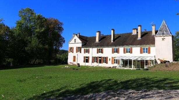 Un grand bâtiment blanc, doté de nombreuses cheminées et d’une véranda en verre.