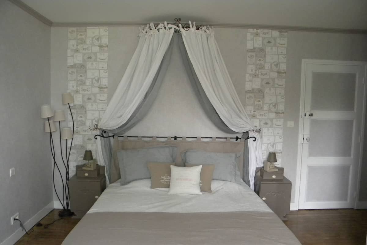 Un dormitorio con cama con dosel, mesitas de noche con lámparas y una puerta.